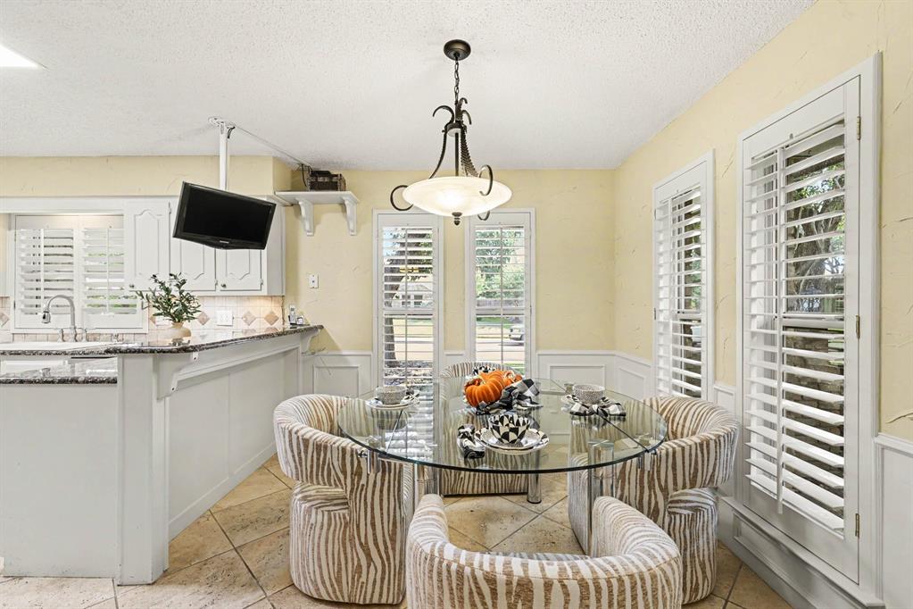 Plantation shutters, tile flooring, built-in shelving, wainscoting, and a ceiling-mounted light fixture