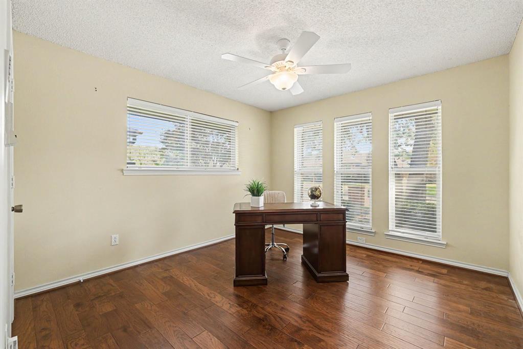 Hardwood flooring, multiple windows with blinds, ceiling fan with integrated lighting, textured ceiling, and light-colored wall paint