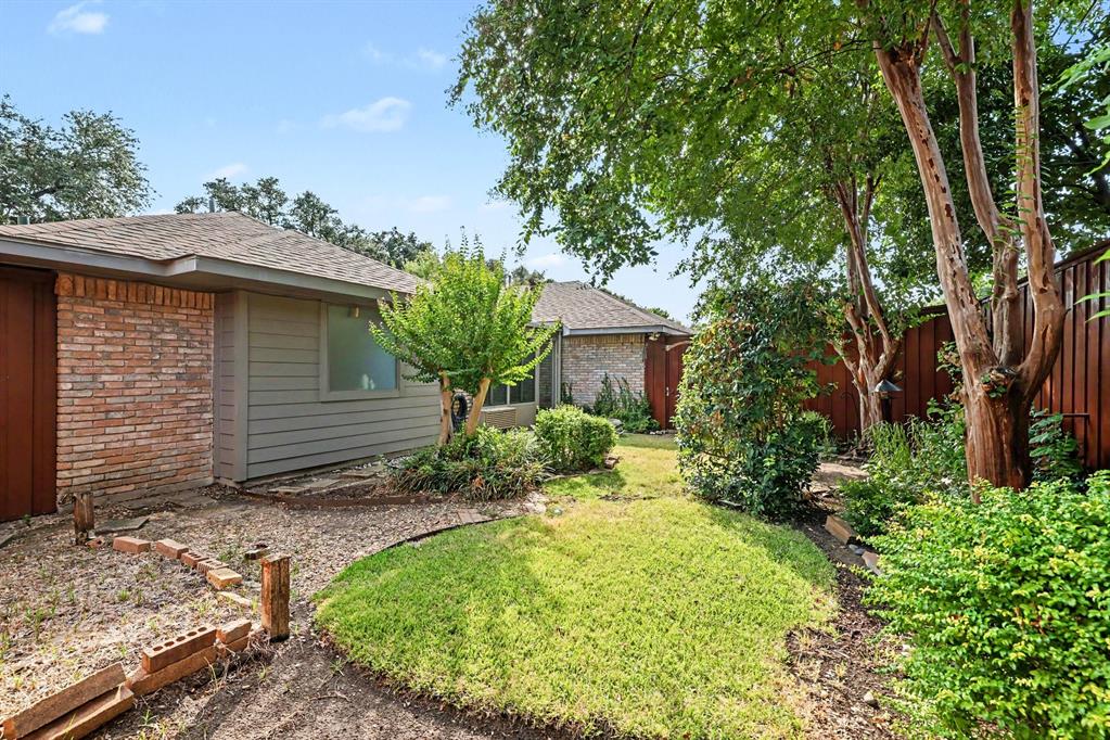 Brick and siding exterior, sloped roofline, mature trees, and privacy fencing