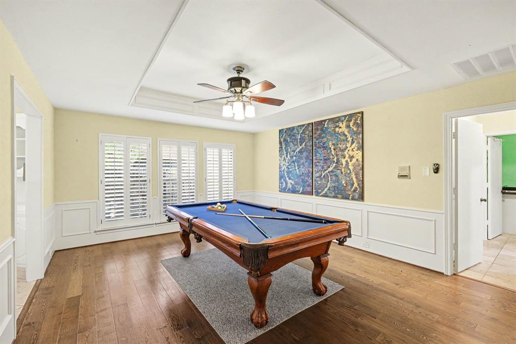 Hardwood flooring, recessed ceiling with fan, wainscoting, and white plantation shutters
