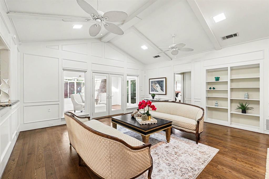 Vaulted ceiling with exposed beams, wood-finish flooring, built-in shelving, panel molding, and French doors Vaulted ceiling with exposed beams, wood-finish flooring, built-in shelving, panel molding, and French doors