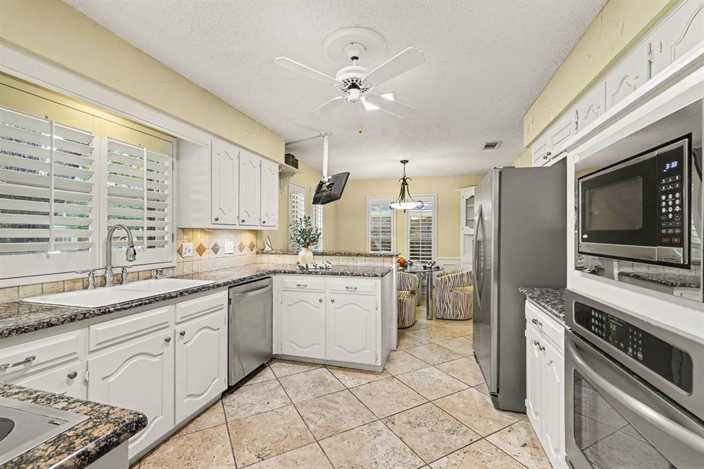 Kitchen featuring white cabinetry, stone-finish countertops, stainless steel appliances, and tile flooring