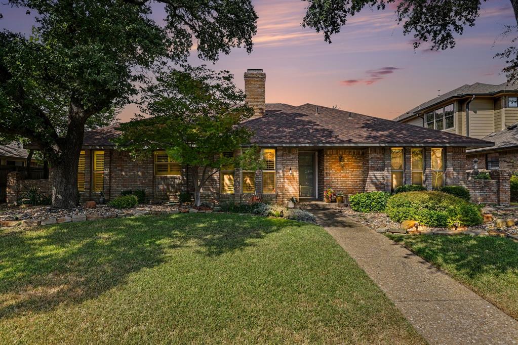 Brick exterior with a prominent chimney, a dark shingle roof, and a concrete pathway leading to the entry Brick exterior with a prominent chimney, a dark shingle roof, and a concrete pathway leading to the entry