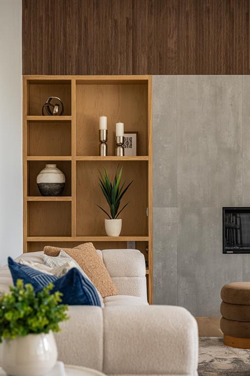 Custom built-in shelving, warm wood tones and fluted walnut accents create a striking architectural focal point, bringing texture and sophistication to the living space.