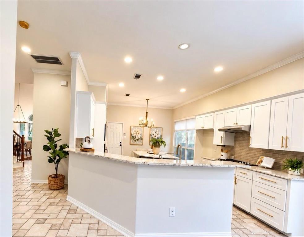 Kitchen featuring white shaker-style cabinetry, granite countertops, a built-in range hood, a tile backsplash, and recessed lighting