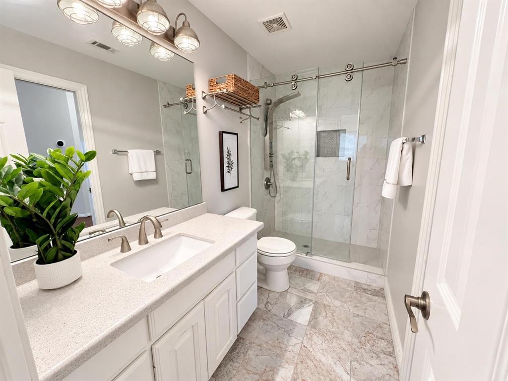 White vanity with a light speckled countertop, undermount sink, and brushed nickel faucet
