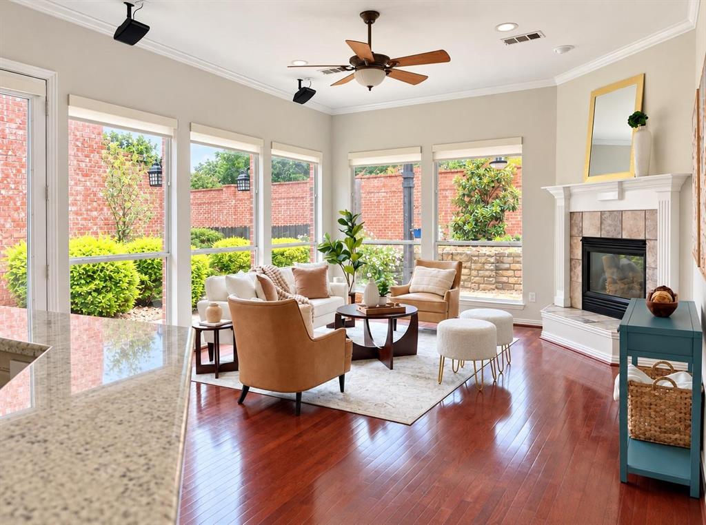Living area featuring rich wood-finish flooring, a ceiling fan, and multiple windows