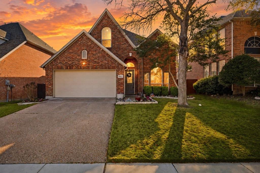 Brick-clad facade with arched windows, attached garage, and a concrete driveway