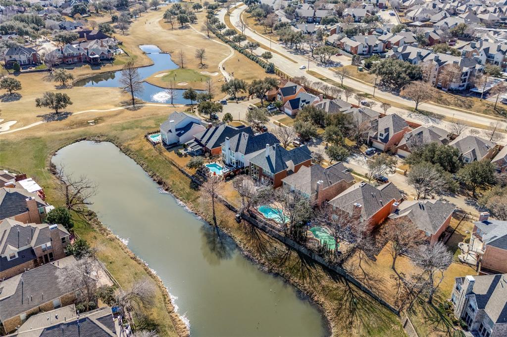 Aerial perspective showcasing a residential community with homes featuring private swimming pools, situated along a waterway, and bordering a golf course with multiple water features