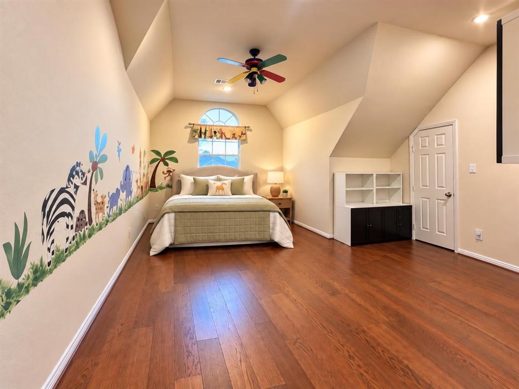 Wood-finish flooring, vaulted ceilings, arched window, built-in shelving, and a ceiling fan