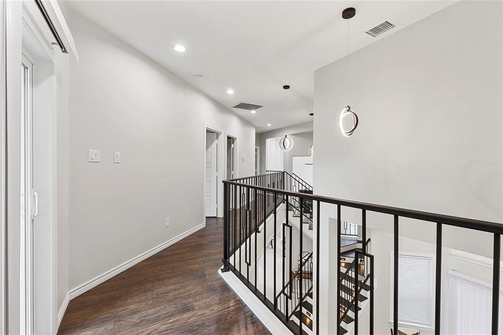 Wood-finish flooring, recessed lighting, contemporary pendant lighting, white walls, and black metal stair railings