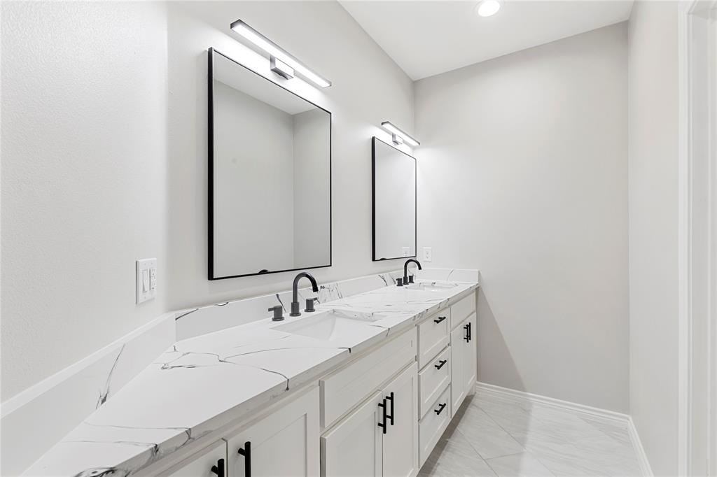 Dual vanities with white cabinetry, black hardware, and integrated sinks