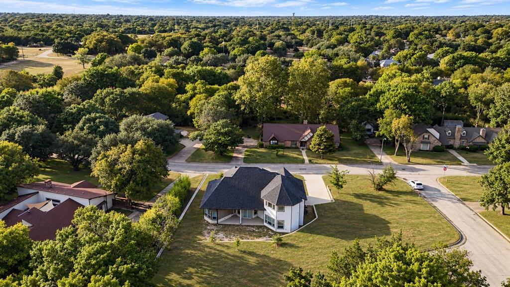 Expansive residential property with a manicured lawn, paved driveway, and mature trees