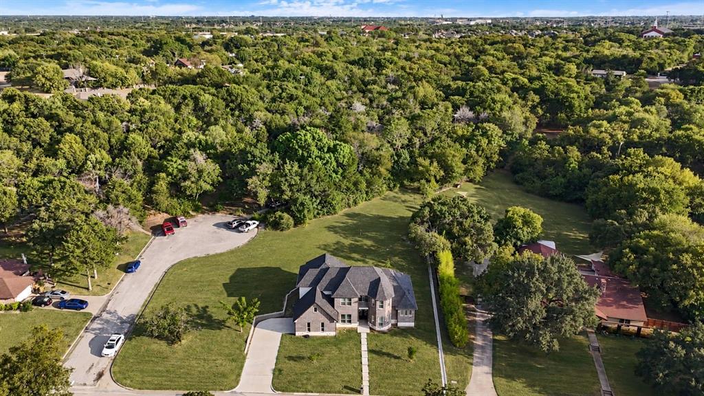 Stone and brick exterior with a multi-gabled roof, expansive green lawn, and concrete driveway