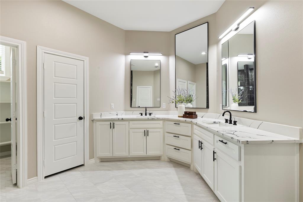 Dual vanities with white cabinetry, integrated sinks, and black fixtures