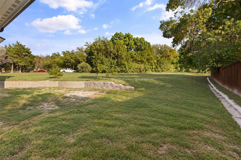 Expansive lawn area with mature trees and a retaining wall