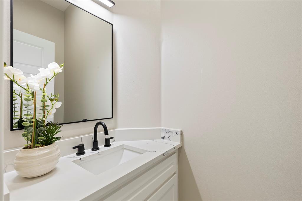 White vanity with a rectangular undermount sink, black matte faucet, and a quartz countertop with a short backsplash