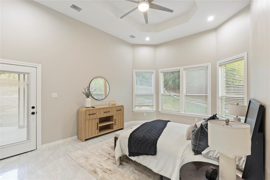 Tray ceiling with recessed lighting and ceiling fan, multiple windows with blinds, glass-paneled exterior door, and tile flooring