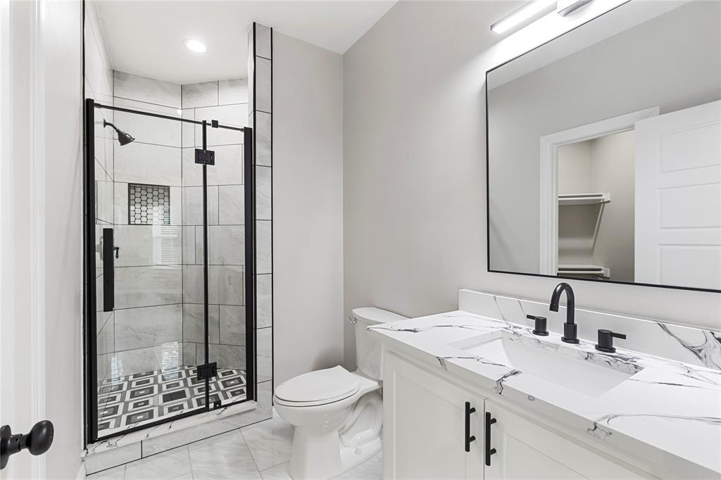 Glass-enclosed shower with black-framed door and patterned tile flooring