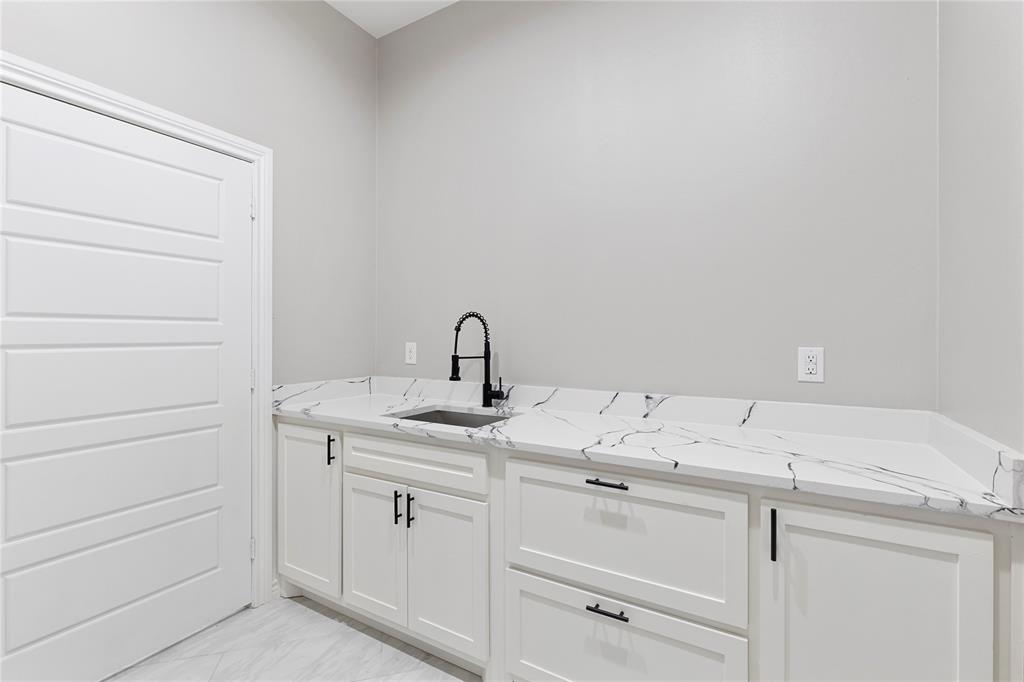 White cabinetry with matte black hardware, integrated sink, and patterned stone-finish countertop