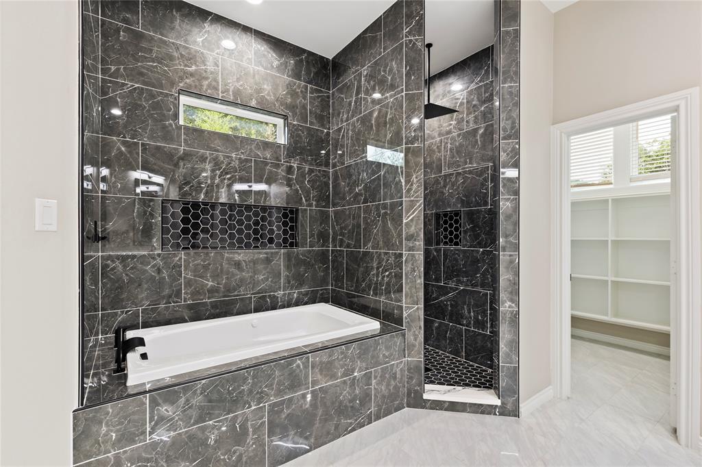 Full-height dark tile surround with integrated bathtub, built-in shower, black fixtures, and recessed lighting