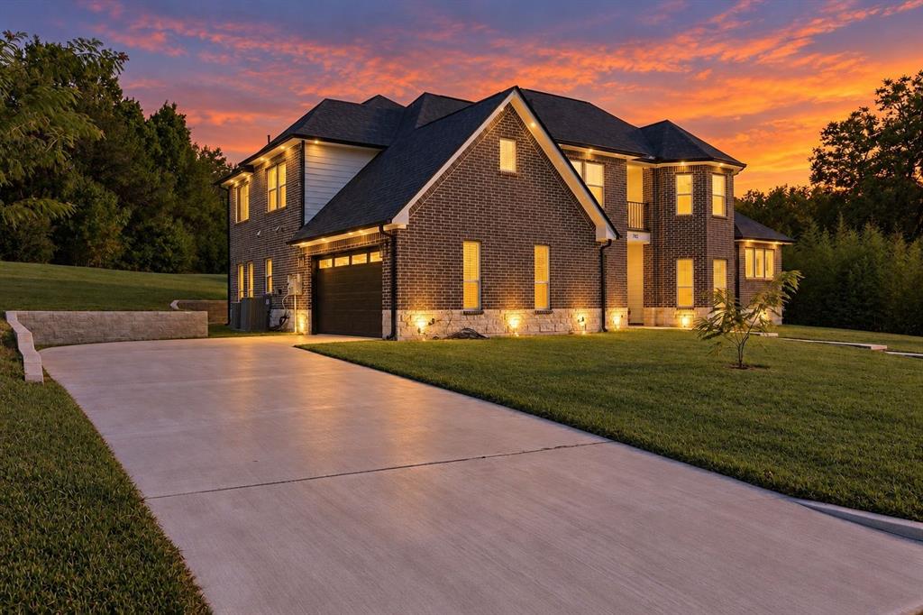 Brick and siding exterior with stone accents, concrete driveway, attached garage, and exterior accent lighting Brick and siding exterior with stone accents, concrete driveway, attached garage, and exterior accent lighting