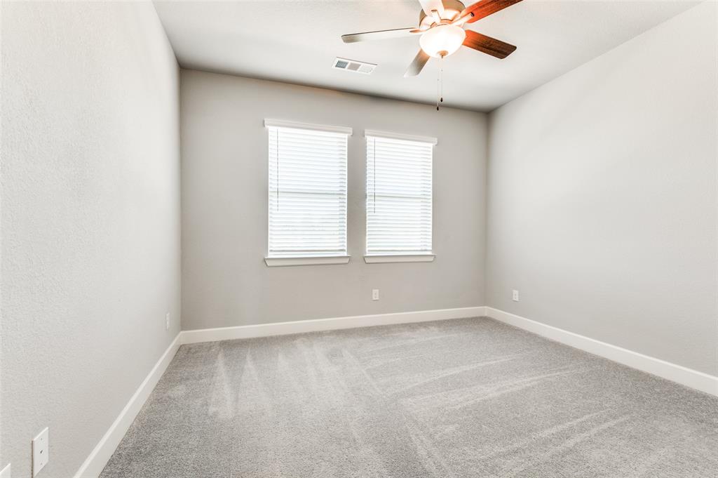 Neutral wall paint, two windows with blinds, ceiling fan with integrated lighting, and gray carpet flooring Neutral wall paint, two windows with blinds, ceiling fan with integrated lighting, and gray carpet flooring