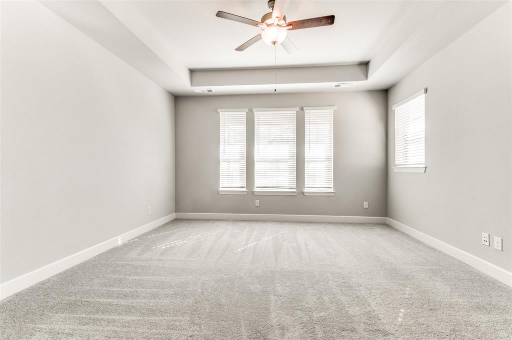 Light gray carpeting, a tray ceiling, and a ceiling fan with light fixture Light gray carpeting, a tray ceiling, and a ceiling fan with light fixture