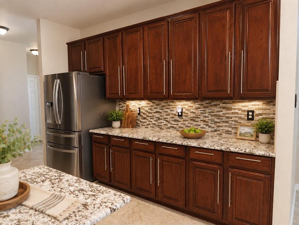 Wood-finish cabinetry paired with granite countertops and a mosaic tile backsplash