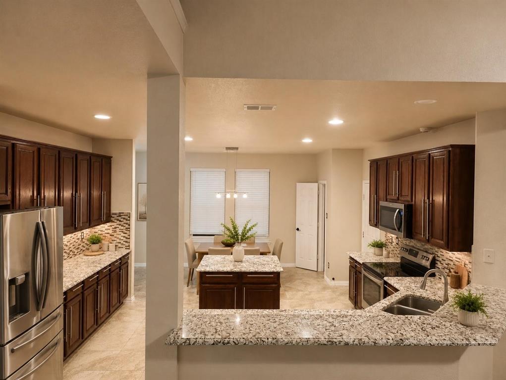 Kitchen featuring wood cabinetry, light-toned stone countertops, and stainless steel appliances