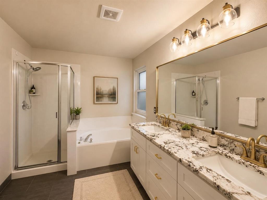 Dual vanity with undermount sinks, granite countertop, frameless mirror, walk-in shower with glass enclosure, and a built-in tub