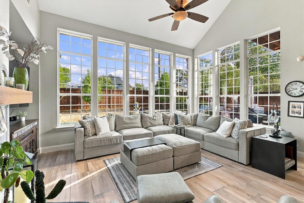 Living area featuring a vaulted ceiling, floor-to-ceiling windows with grid detailing, wood-finish tile flooring, and a ceiling fan