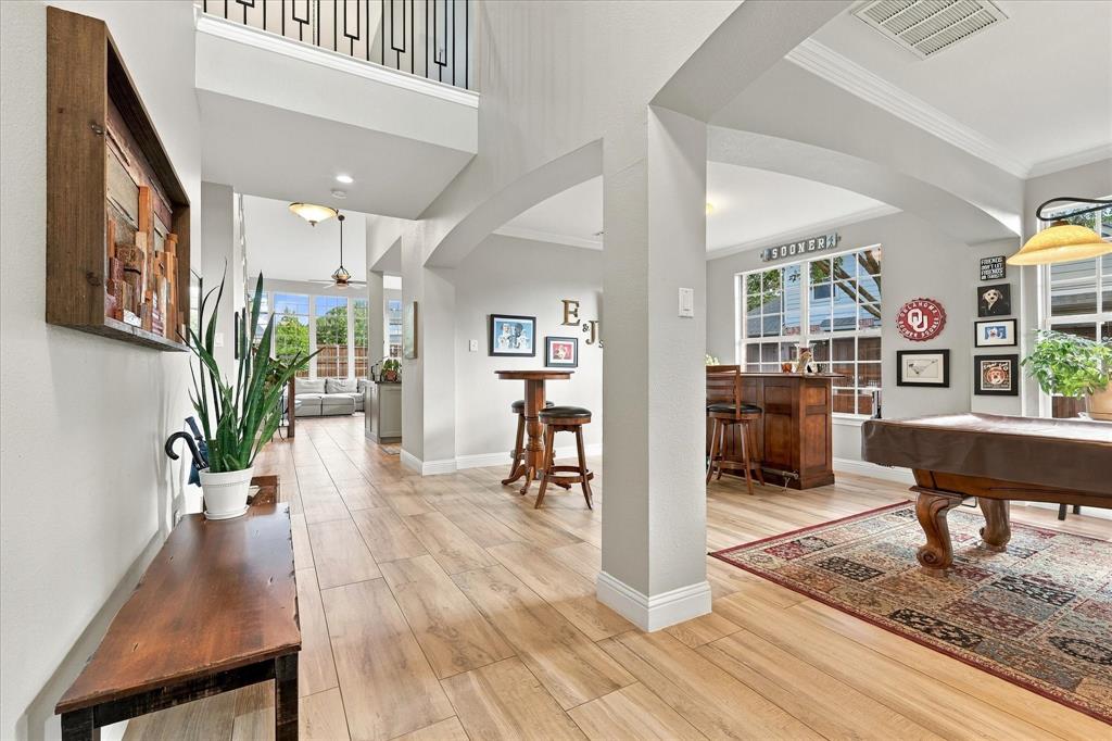 Open-concept interior featuring wood-finish flooring, high ceilings, architectural arched doorways, and metal-railing stair detail