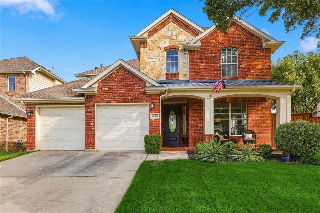 Two-story brick and stone facade featuring a covered front porch, arched window detailing, and a two-car garage