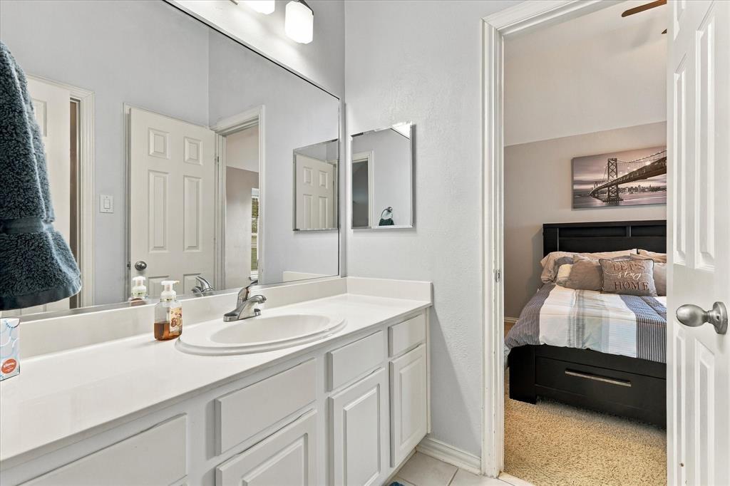Vanity with a solid-surface countertop, an integrated oval sink, chrome faucet, wall-spanning mirror, and white shaker-style cabinetry