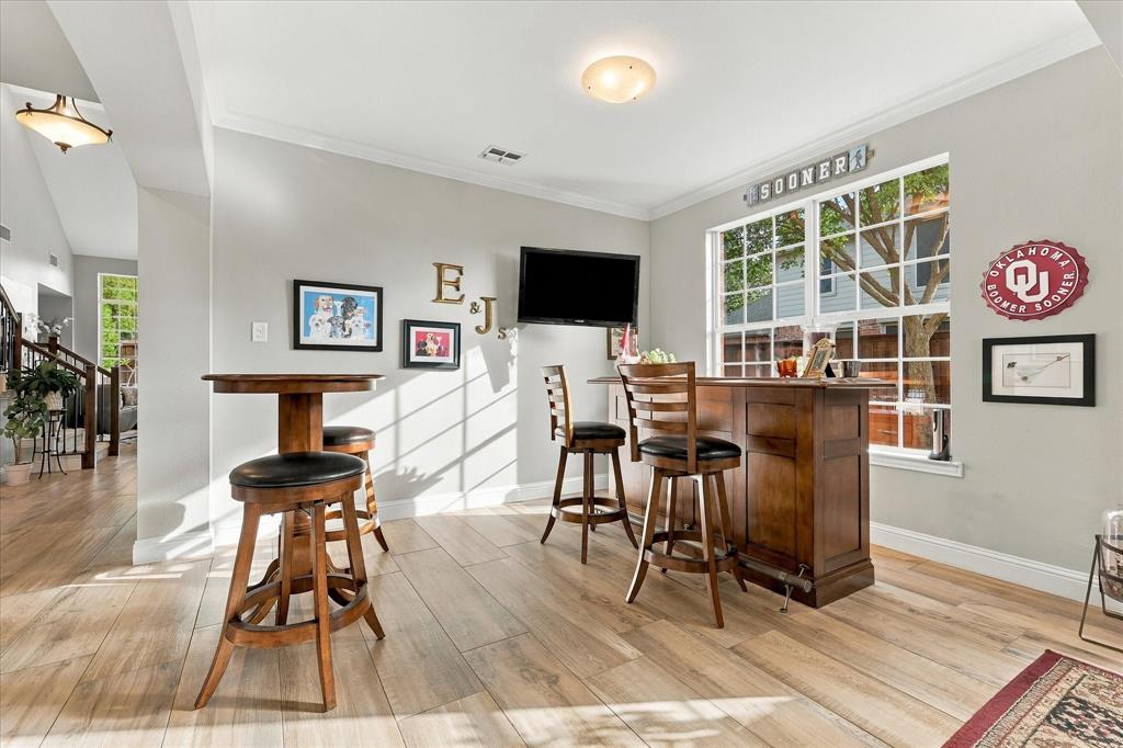 Wood-finish flooring, crown molding, and large grid-pattern windows