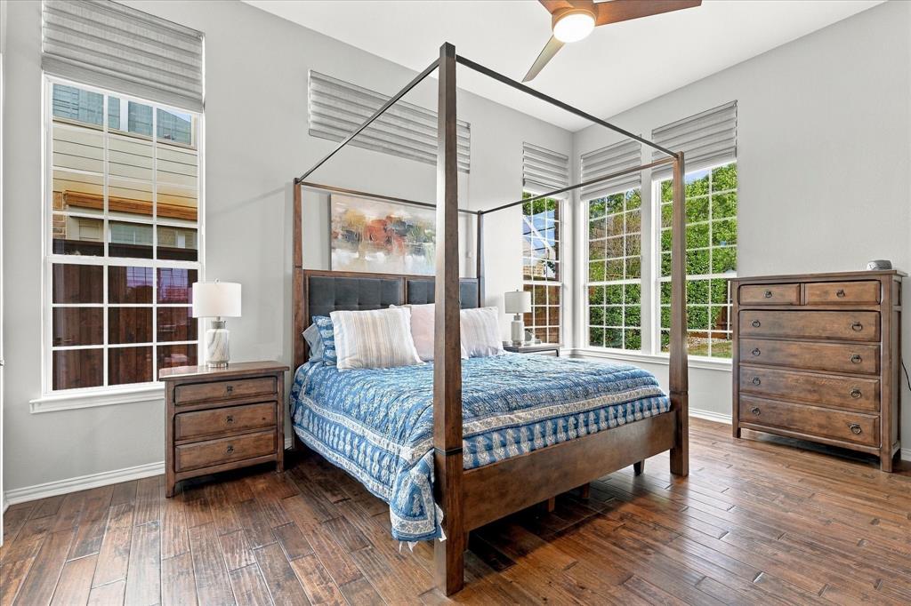 High ceilings featuring a multi-blade ceiling fan, expansive grid-pattern windows, neutral wall palette, and wide-plank wood-finish flooring