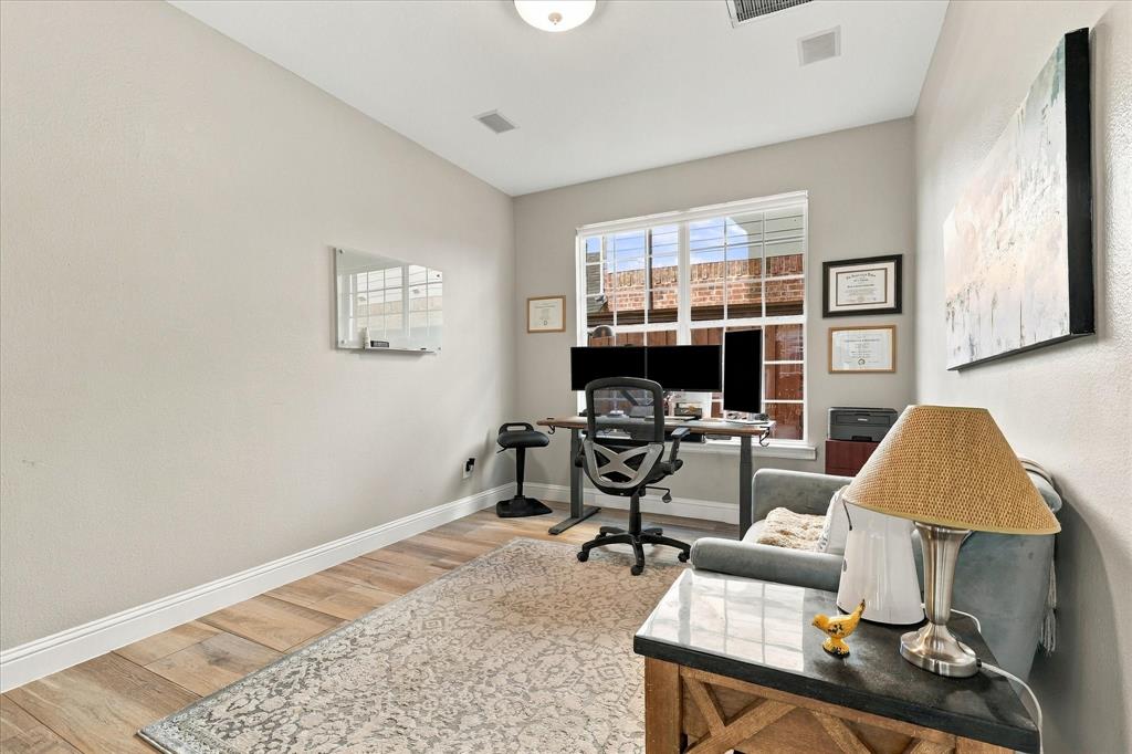 Neutral-toned interior space featuring high ceilings, wood-finish flooring, a multi-pane grid window, and a flush-mount light fixture