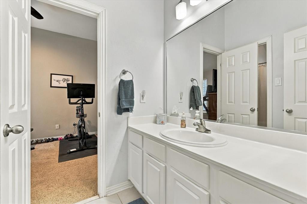 White vanity cabinetry featuring a solid surface countertop, integrated oval basin, metallic hardware, and an expansive wall-mounted mirror
