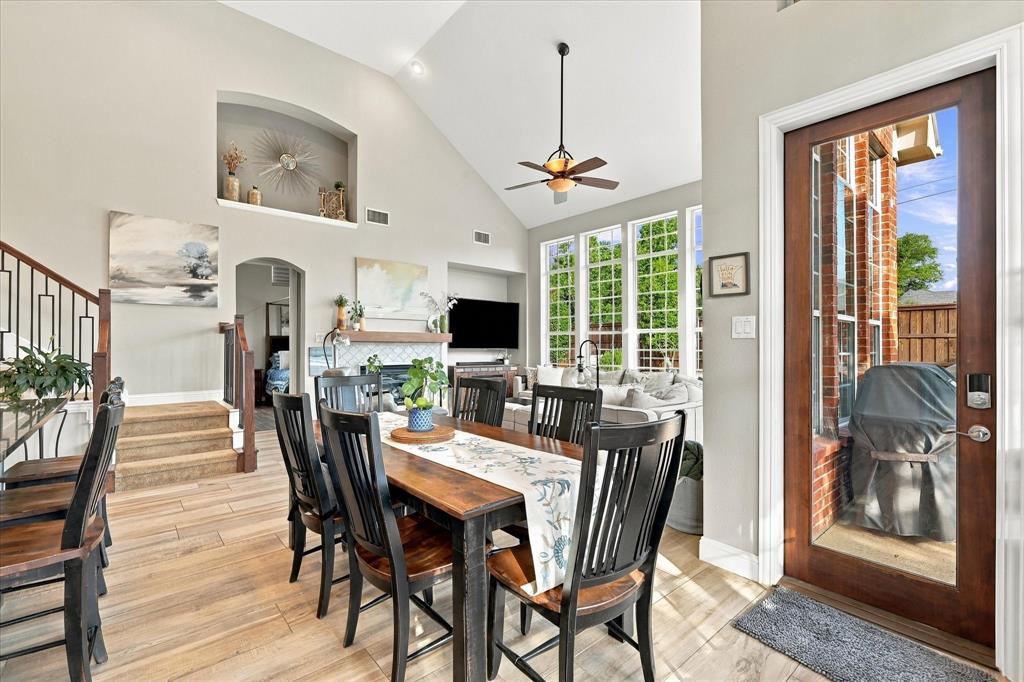 Vaulted ceilings with recessed architectural niches, wood-finish flooring, floor-to-ceiling grid windows, a gas fireplace with a decorative tile surround, and a full-light glass panel exterior door