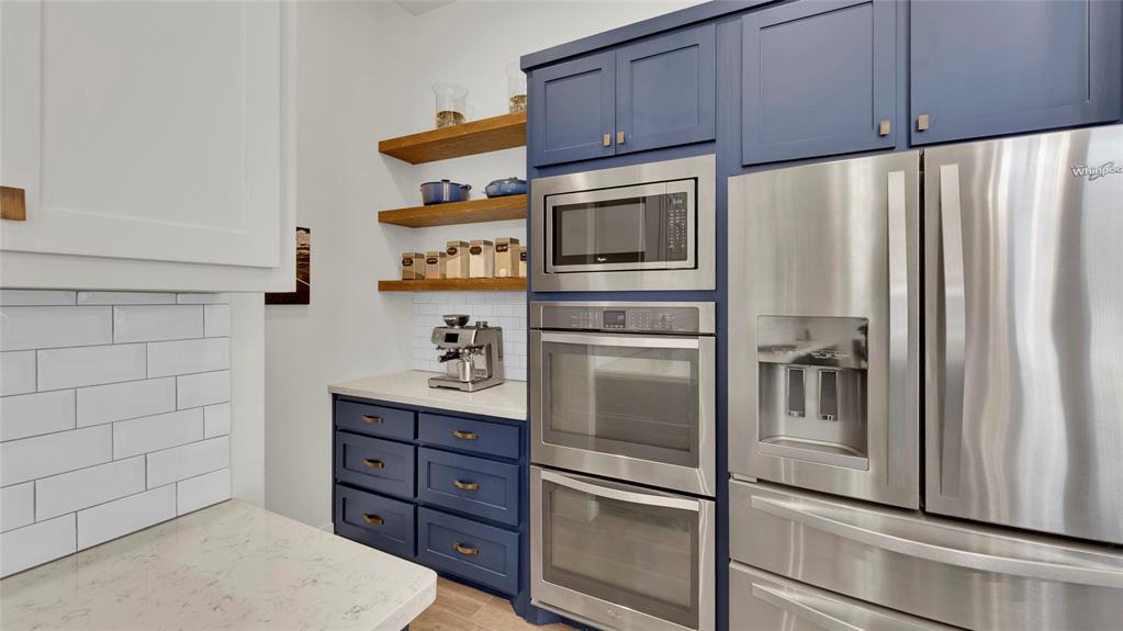 Stainless-Steel appliances, double-oven, coffee bar with shelving and additional storage.