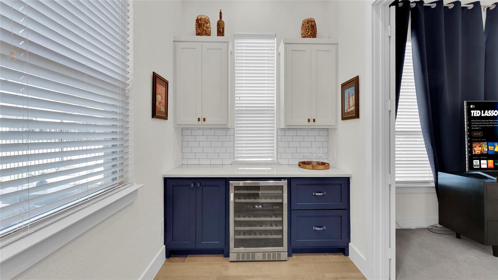Built-in wine bar with beverage fridge, quartz counter, and upper and lower cabinets.