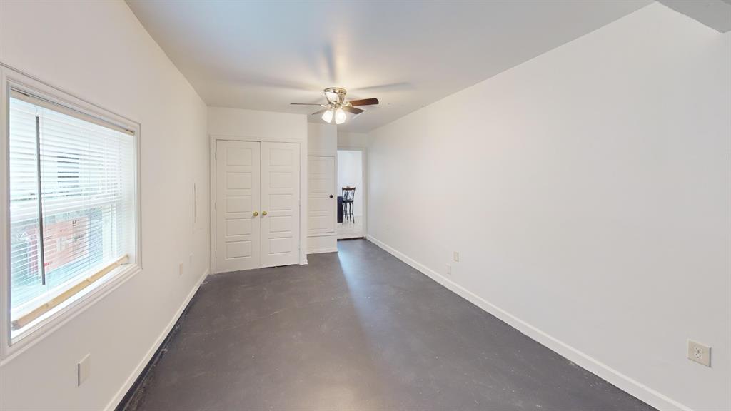 Spacious room featuring a ceiling fan, window with horizontal blinds, and a pair of white paneled closet doors