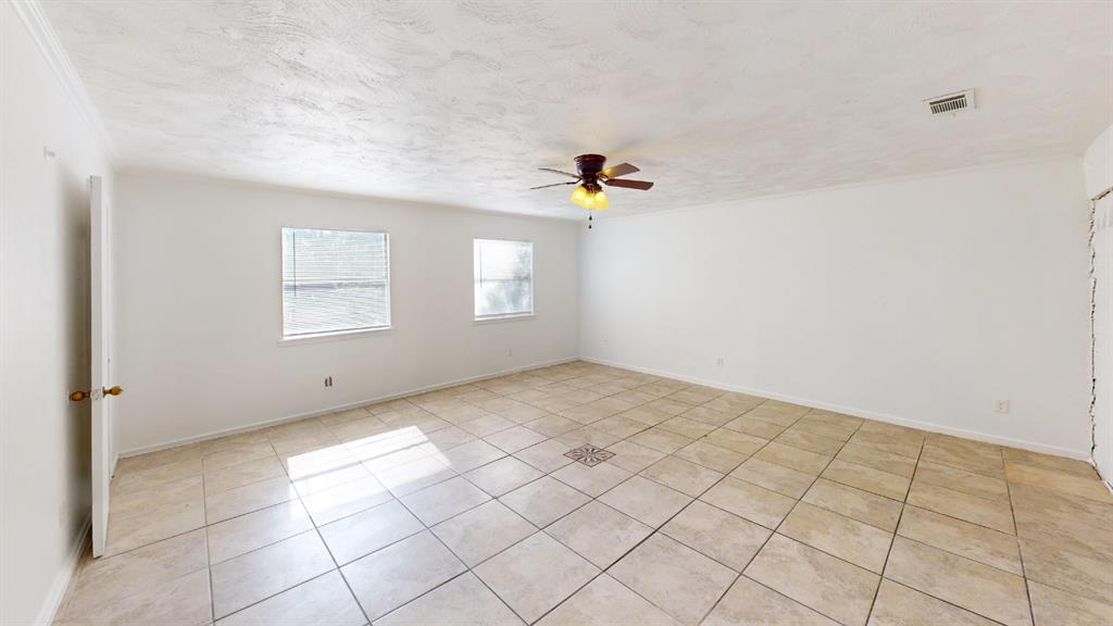 Spacious room featuring tile flooring, a ceiling fan with integrated lighting, and multiple windows