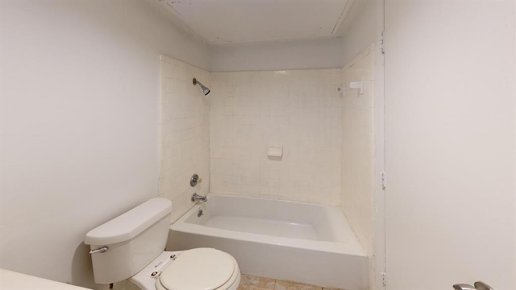 White porcelain toilet and bathtub with tiled shower surround