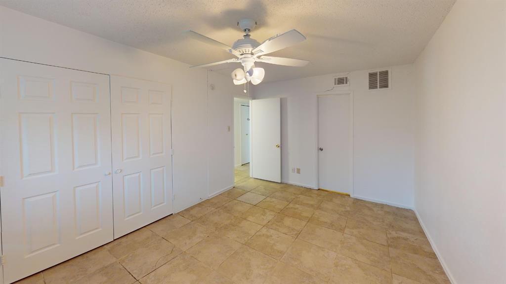 Tile flooring, white walls, ceiling fan with light fixture, white interior doors, and a white six-panel bi-fold closet door