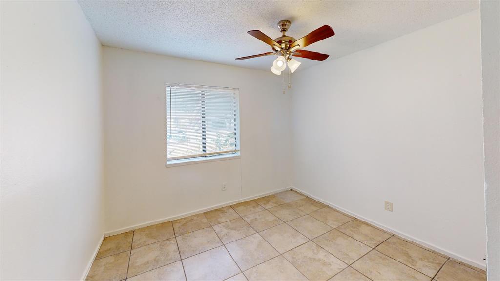 Neutral wall color, window with blinds, ceiling fan with integrated lighting, and tile flooring