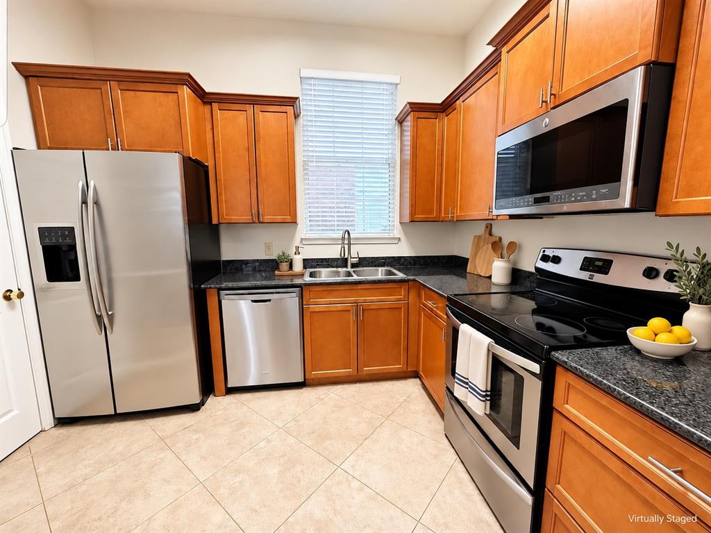 Kitchen featuring wood cabinetry, stainless steel appliances, granite countertops, and tiled flooring