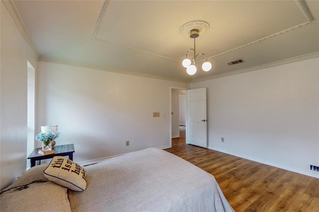 Wood-finish flooring, white walls, decorative ceiling molding, and a modern ceiling light fixture