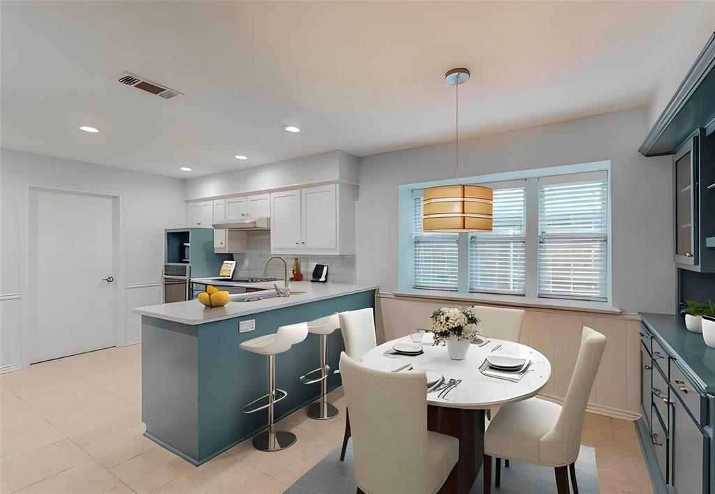 Kitchen featuring an island with counter seating, white upper cabinetry, light-colored tile flooring, stainless steel appliances, and a window with blinds